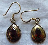 Front view of the earrings showing pear-shaped garnet stones and gold washed sterling silver setting with twisted rope detail