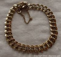Full view of the vintage gold filled double curb link bracelet showing the links, clasp, and safety chain on a light fabric background.