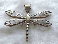 Top down view of sterling silver dragonfly pendant showing open filigree wings with heart-like cutouts and scalloped bail.