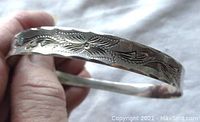 Front side close-up showing detailed floral engraved pattern on sterling silver bangle bracelet.
