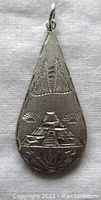 Close-up of the pendant front showing engraved pyramid motifs on brushed sterling silver surface