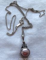 Sterling silver chain laid out with the pink mabe pearl pendant attached, showing clasp and chain details.