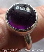 Close-up frontal view of dark amethyst cabochon mounted in sterling silver ring showing rich purple color and smooth dome shape.