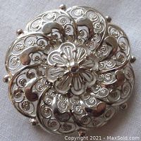 Front view of the vintage sterling silver brooch showing intricate open work filigree details and floral central motif.
