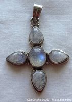 Front view of the pendant showing five bezel set moonstone cabochons in sterling silver, one oval center and four surrounding tear drop shapes.