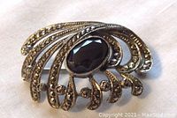 Front view of the brooch showing the black center stone and marcasite decoration in art deco design.
