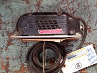 Top view of the 1950s Weller electric sander, showing the attached power cord and sanding base with attached sandpaper.