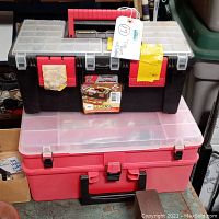 View showing two stacked tool boxes, black Rimax toolbox on top with red handle and clear lid, red translucent toolbox below with multiple compartments