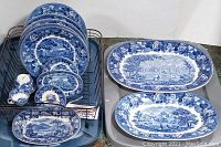 Full lot displayed showing plates in a holder, with serving platters and cup/saucer sets arranged beside them