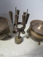 Close-up photo showing the 8 candle holders of the brass vintage menorah with Yad Vashem Jerusalem inscription and the two brass planter pots with lids and lion-shaped feet.