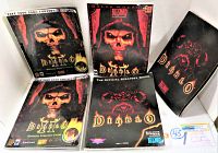 Five Diablo and Diablo II PC game strategy guides and manuals arranged in a cluster showing cover artwork with skull and demon faces on dark backgrounds.