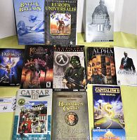 Overhead image showing 12 PC game guides and manuals neatly arranged, including titles like Battle of Britain, Europa Universalis, Half-Life: Opposing Force, Sid Meier's Alpha Centauri, and more.