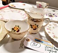 Photo showing several pieces including a teacup, cream jug and plate with yellow rose floral design and gold trim