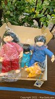 Four dolls arranged in a box, wrapped partially in plastic wrap, showing their size and details.