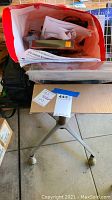 Red and white container on rolling stand with assorted papers and office items
