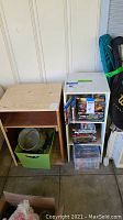 Two small shelves side by side; the white shelf rolls, the wooden shelf does not. Various items stored inside but contents excluded from sale.