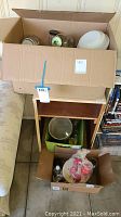 Boxes and containers with various glass and plastic jars and bowls stacked on a small shelf