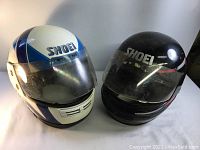 Pair of two SHOEI motorcycle helmets side by side showing overall condition and style.