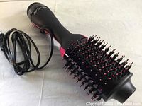 Full view of the Revlon Salon One-Step Hair Dryer and Volumizer showing black body with pink highlights, bristles, and power cord.