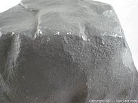 Close-up photo of the KLIPSCH outdoor speaker designed to look like a rock, showing its surface texture and minor scratches.