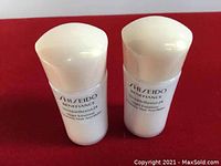 Front view of two white bottles of Shiseido Benefiance Wrinkle Resistant 24 Night Emulsion placed on red background showing product name.