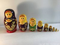 Full set of 9 Russian/Ukrainian nesting dolls lined up by size, showing various hand-painted floral and face details.