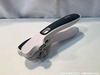 Zyliss Lock n Lift can opener folded, showing black and white ergonomic handle and metal cutting gears.