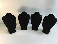 Four black velvet necklace display mannequins placed upright, showing front view with uniform shape and size.