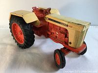 Front-right angle view of diecast CASE 1030 tractor showing detailed engine and front grill painted cream with orange body.