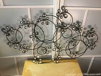 Full view of vintage metal wall plaque with multiple circular wire swirls and embedded clear crystal rhinestones.