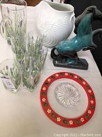 Photo showing entire lot arrangement including blue ceramic horse, white vase, red candle holder, glass dish, six hand-painted glasses, and glass pitcher.
