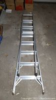 Full view of the ladder lying flat showing the extendable sections and rungs.
