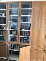 Front view of the cabinet showing glass door compartments with lock and wooden doors below with handles.