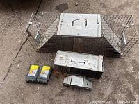 Overview of all traps on ground, showing three metal live traps and two plastic mouse snap traps