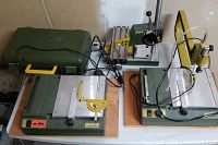Three Proxxon benchtop tools and storage case on work surface