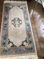 Full view of carpet runner on wooden floor showing central floral medallion and border design.