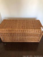 Front view of the wicker blanket chest showing the tightly woven wicker and hinged top.