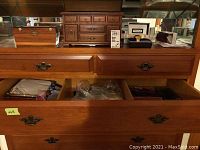 Glass display cabinet drawers open showing various clutches, purses and handkerchiefs