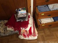 Woven fringed blankets layered with some papers and other items on top, assorted towels in open drawers.