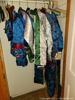 Six varied satin and brocade jackets and robes hanging on a closet rod