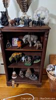 Shelf displaying multiple wildlife figurines including bears, buffalo, wolves, and a small orange owl, with dream catchers on top and Native American themed small teepee figurines on lower shelves.