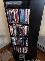 Photo of black shelving unit filled with DVDs and VHS tapes with visible movie titles