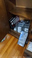 Oneida flatware sets and Forever Sharp Platinum series knife sharpener boxed and stored in wooden cabinet lower shelf.