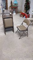 Six brown-tan vinyl padded metal folding chairs, five stacked and one set up, visible wear and tear.