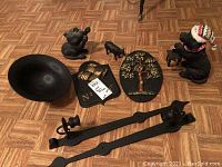 Wide shot showing all metal plaques, candle sconces, black bowl, and several cat and dog figurines placed on wooden floor