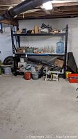 Wide view of black metal shelf loaded with miscellaneous items in basement setting