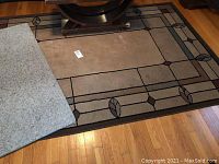 Photo showing Shaw Carpet area rug with beige and geometric border design and smaller grey throw rug partially overlapping it.