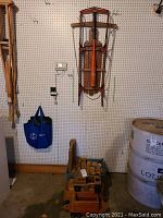 Wide shot showing the Flexible Flyer sled hanging on a wall, blue hanging bag, and the wooden toy truck on floor with wooden blocks in it.