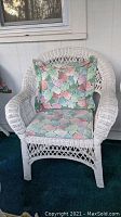 White wicker chair with pastel multicolor patterned seat and back cushions, showing chair detail and fabric pattern