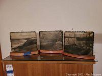 Three vintage night lights on wooden bases with black and white scenic photos, showing coastal and harbor scenes, on a wooden cabinet.